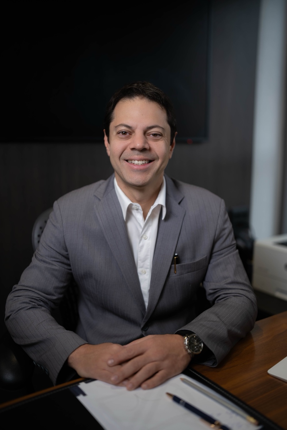 Dr. Flavio Pestilla Esperidião, urologista, sorrindo à mesa de seu consultório
